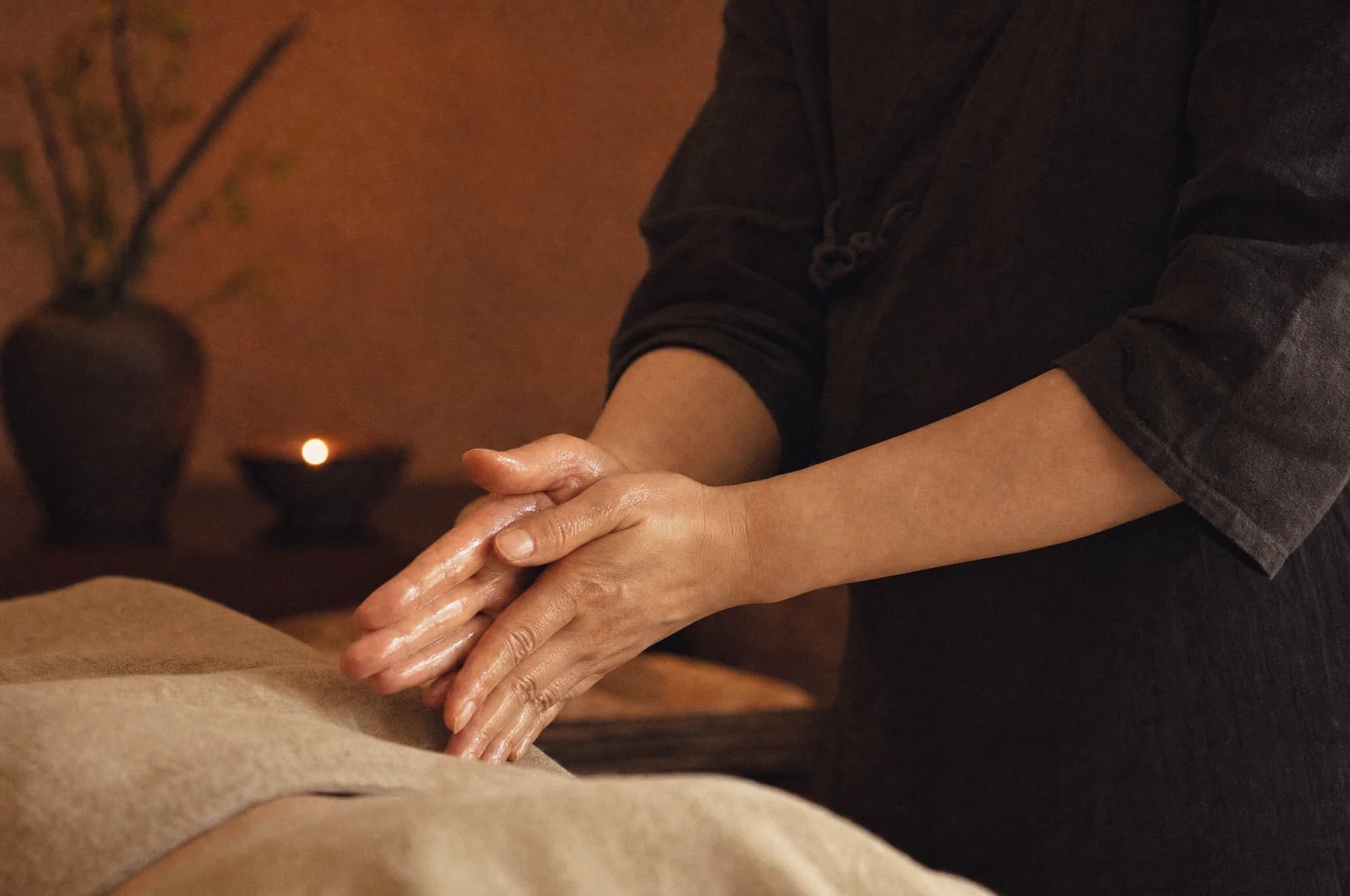 Masseuse wrijft olie warm tussen haar handen boven de massagetafel